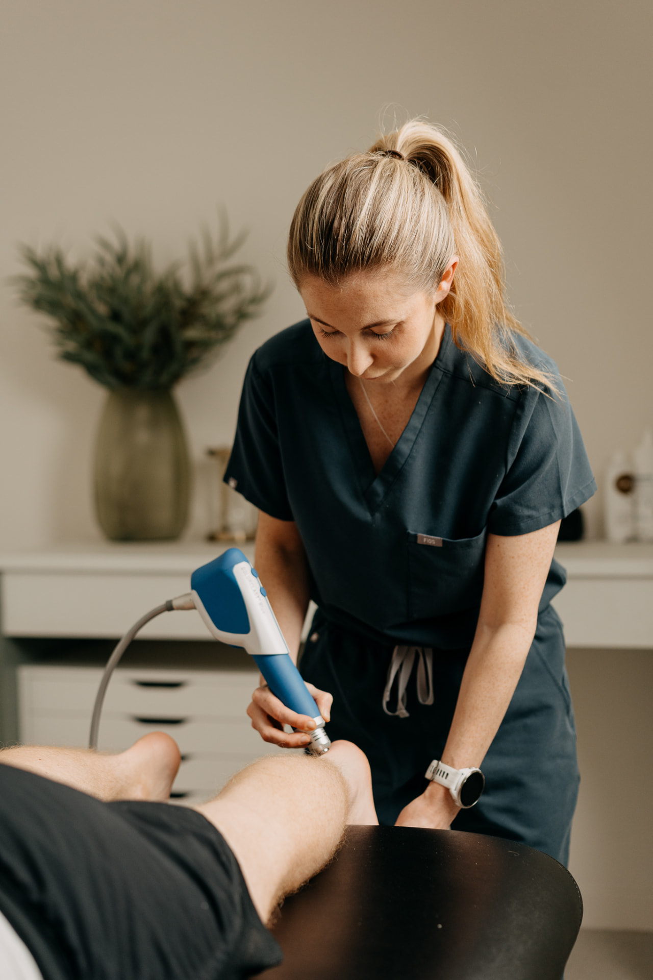 Clinician applying shockwave therapy to a patient's calf at Assure Health in Carryduff, Belfast