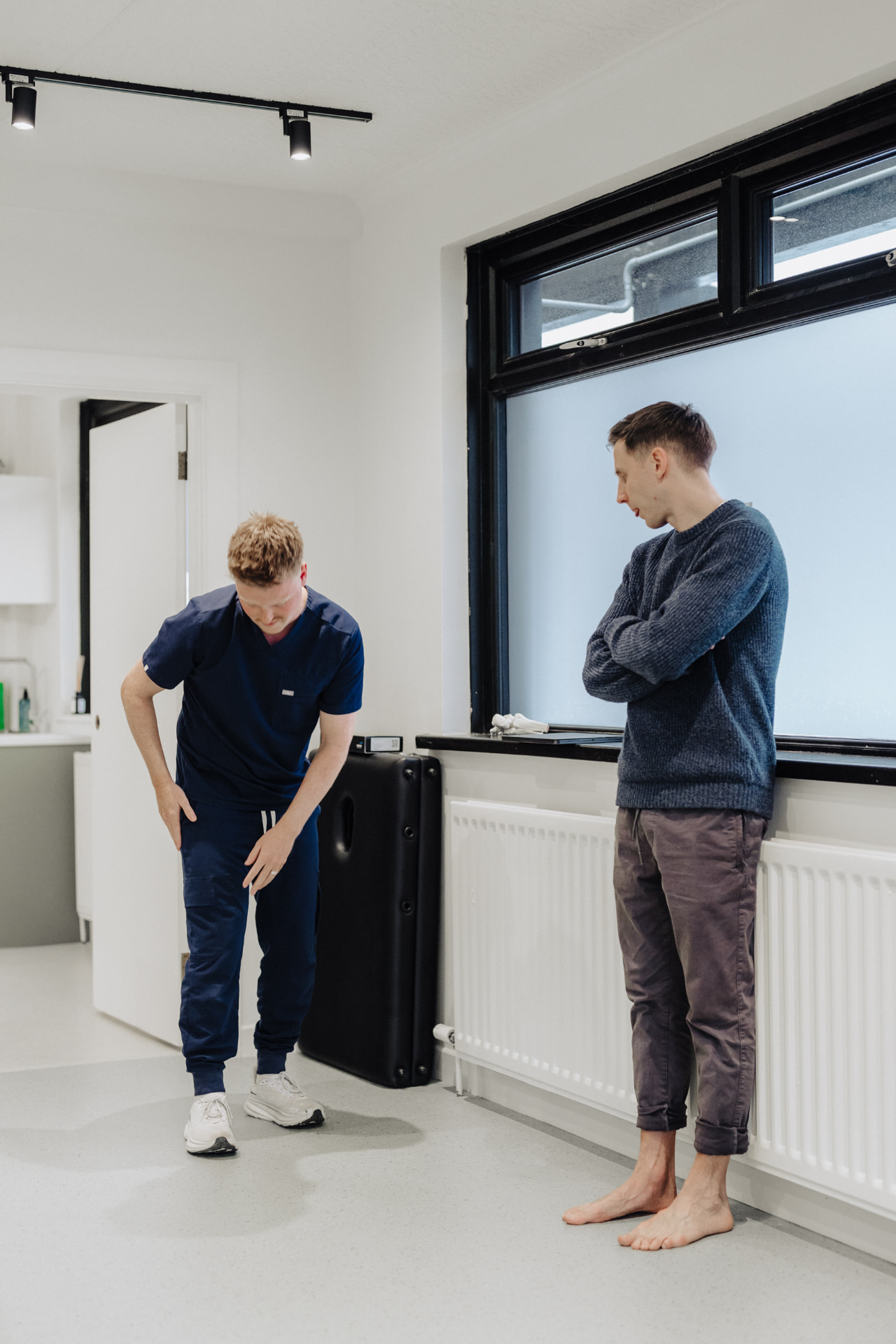 Podiatrist assessing a runner's shin and lower leg at Assure Health in Carryduff, Belfast