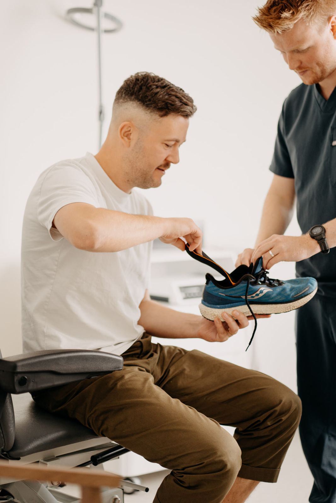 Podiatrist fitting a custom orthotic into a patient's running shoe at Assure Health in Carryduff, Belfast