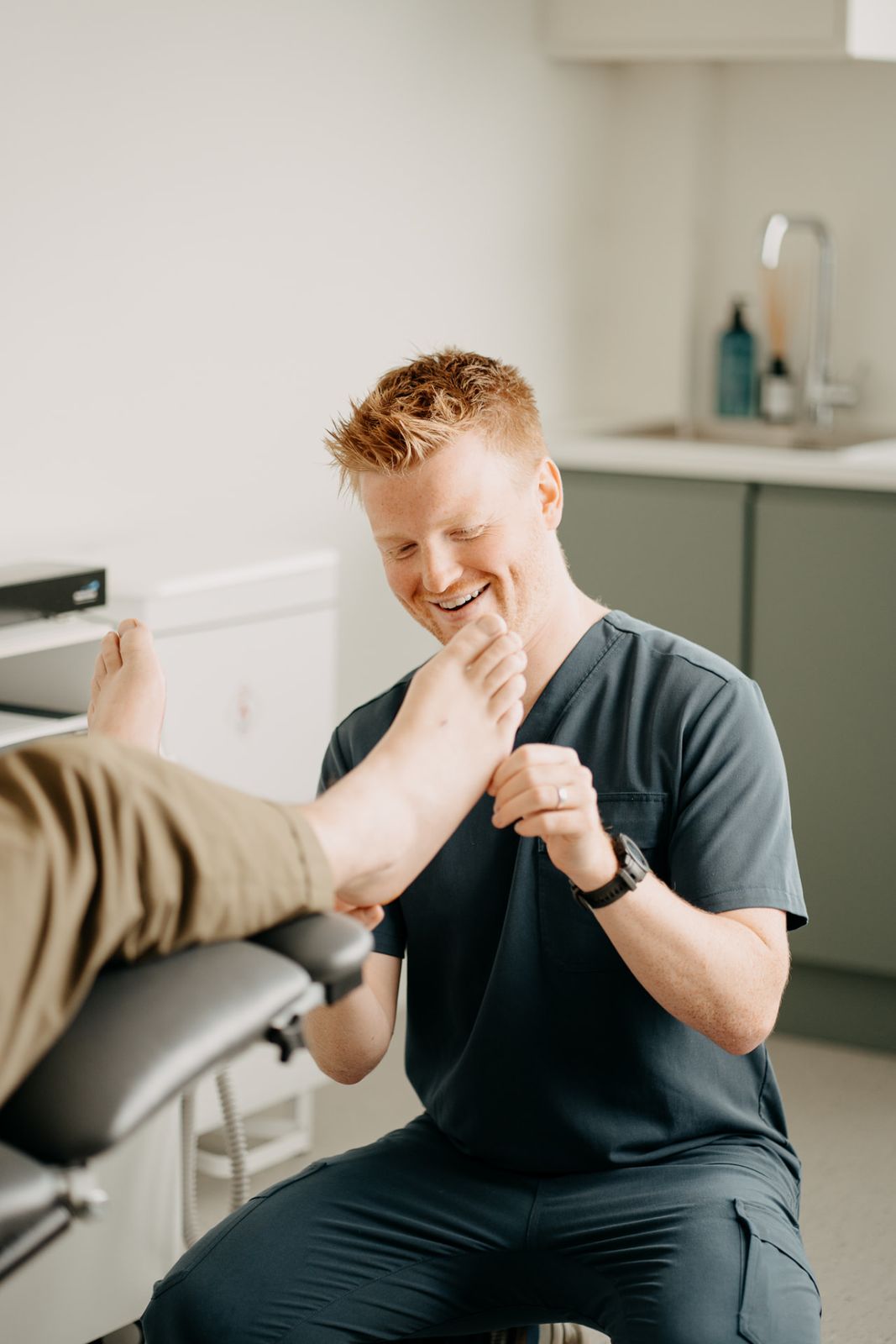 HCPC registered podiatrist assessing a patient's foot at Assure Health, Belfast