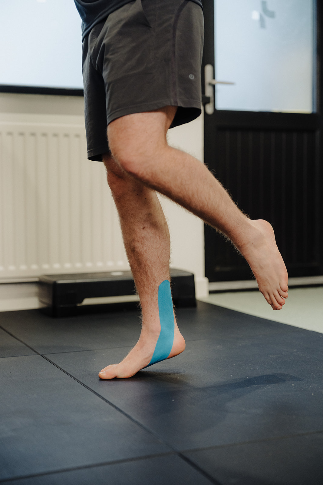 Patient carrying out a progressive Achilles loading exercise with a physiotherapist at Assure Health in Carryduff, Belfast